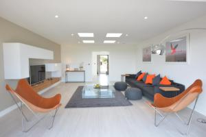 a living room with a black couch and orange chairs at Skylight, Aldeburgh in Aldeburgh