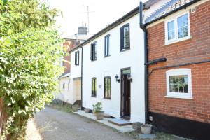 una casa blanca con una puerta negra en una calle en Pine Cottage en Woodbridge