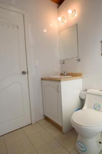 La salle de bains blanche est pourvue de toilettes et d'un lavabo. dans l'établissement Casa Elalu, à Quito