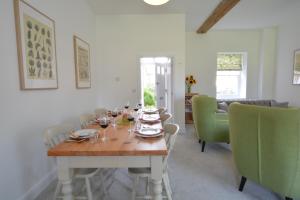a dining room with a wooden table and green chairs at Ploughman's Green, Blythview in Blythburgh
