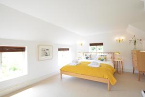 a white bedroom with a yellow bed and windows at River View, Pin Mill 
