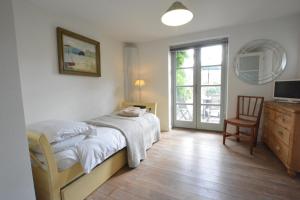 a bedroom with a bed and a chair and a window at Robert Sadler's Studio in Aldeburgh