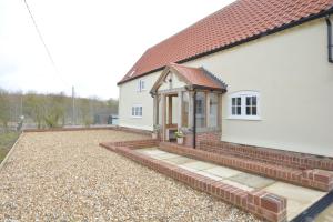 a white house with a red roof and a patio at Woodland Cottage, Great Glemham in Framlingham