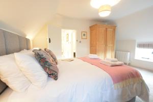 a bedroom with a large white bed with white pillows at Woodland Cottage, Great Glemham in Framlingham