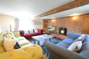 a living room with couches and a brick wall at The White House with Studio in Homersfield