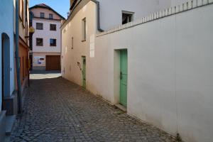 an empty alley with green doors and buildings at Sklep jinak in Jihlava