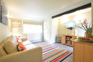 a living room with a couch and a television at Church Farm Cottage, Dunwich in Westleton
