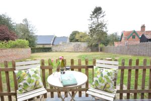 two chairs and a table on a patio with a fence at Church Farm Cottage, Dunwich in Westleton