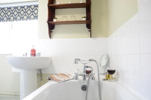 a bathroom with a bath tub and a sink at Church Farm Cottage, Dunwich in Westleton +12 photos
