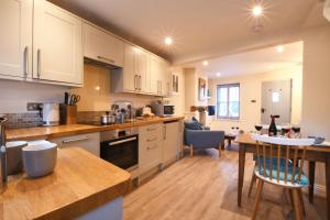 uma cozinha com armários brancos, uma mesa e uma sala de jantar em Smugglers Rest, Aldeburgh em Aldeburgh