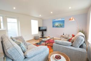 uma sala de estar com dois sofás e uma televisão em Bramertons Nest, Long Melford em Long Melford