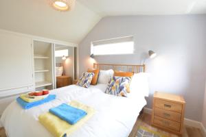 um quarto com uma cama branca e toalhas em Bramertons Nest, Long Melford em Long Melford