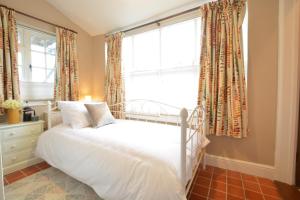 a bedroom with a white bed and a window at Corner Cottage, Dennington in Framlingham