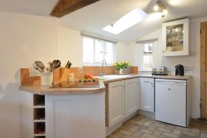 a kitchen with white cabinets and a sink at The Moorings, Orford in Orford