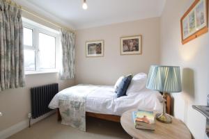 um quarto com uma cama e uma mesa com um candeeiro em Napier House, Southwold em Southwold