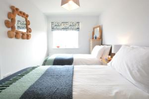 a bedroom with two white beds and a window at Lapwings, Aldeburgh in Aldeburgh
