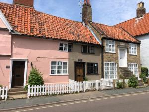 a pink house with a white fence at Rosemary Cottage, Aldeburgh in Aldeburgh