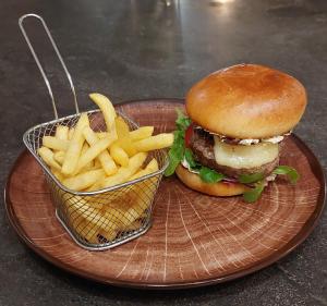 une assiette avec un hamburger et un panier de frites dans l'établissement Logis Le Prieuré, à Locronan