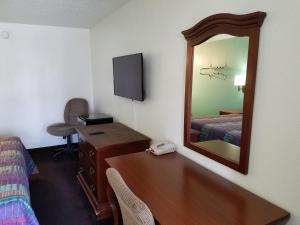 a hotel room with a desk and a mirror at IndySouth Western Inn in Indianapolis