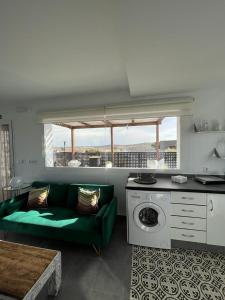 a living room with a green couch and a kitchen at El Gallinero in Almoharín