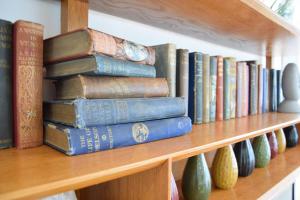 a stack of books on a shelf with vases at Marsh View, Southwold in Southwold