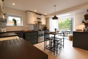 a kitchen with white cabinets and a table and chairs at Marsh View, Southwold in Southwold