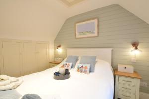 The Smokehouse Cottage في ساوثوولد: غرفة نوم بسرير ابيض مع مخدات زرقاء