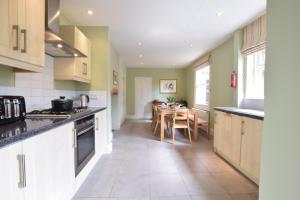 a kitchen with white cabinets and a dining room with a table at 14 Dunwich Road, Southwold in Southwold