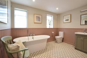 a bathroom with a tub and a toilet at Satis Cottage, Westleton in Westleton +24 photos