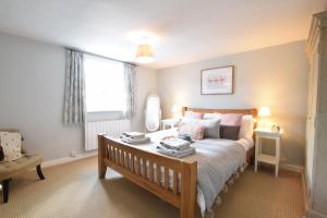 a bedroom with a bed and a chair and a window at Satis Cottage, Westleton in Westleton