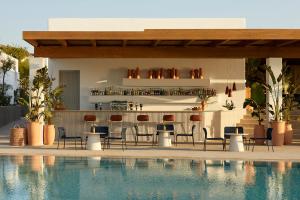 a bar with chairs and tables next to a swimming pool at PAROCKS Luxury Hotel & Spa in Ambelas