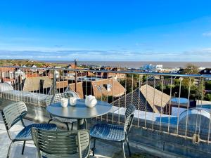 una mesa y sillas en un balcón con vistas al océano en Pier View, Southwold en Southwold