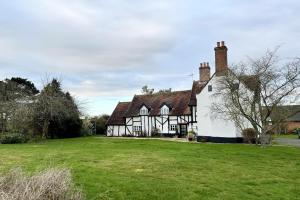 una vieja casa en blanco y negro con un patio verde en Church Farmhouse, Cookley, en Halesworth