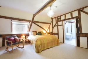 Un dormitorio con una cama y una silla en una habitación. en Church Farmhouse, Cookley, en Halesworth
