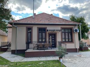 a small house with a balcony with a table at Kovács Apartmanház in Kiskunhalas