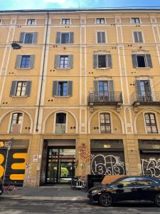 un edificio giallo con un'auto parcheggiata di fronte di Ripa Apartments Milano - Vigevano a Milano