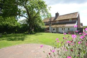 une maison avec un jardin orné de fleurs roses au premier plan dans l'établissement Shoemakers Cottage, Friston, à Friston