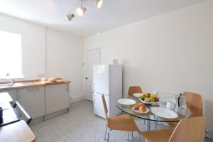 a kitchen with a table and a white refrigerator at Driftwood, Southwold in Southwold +16 photos