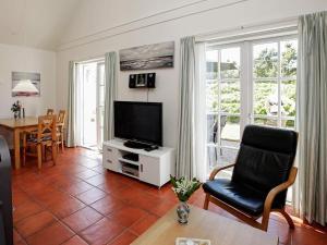 a living room with a tv and a chair and a table at 4 person holiday home in Bl vand in Blåvand