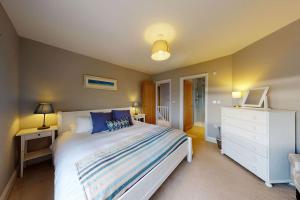 1 dormitorio con 1 cama blanca y vestidor blanco en Derwen, en Abersoch