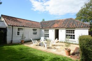 Casa blanca con sillas y patio en Fig Cottage, Pettistree, en Woodbridge