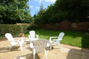 4 sillas blancas y una mesa en el patio en Fig Cottage, Pettistree, en Woodbridge