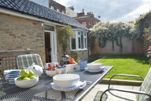 einen Tisch mit Schalen und Teller mit Speisen auf einer Terrasse in der Unterkunft Garden Cottage, Southwold in Southwold