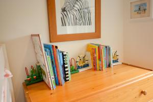 a row of books sitting on top of a wooden shelf at Three Chantry Barns, Orford in Orford