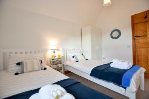 two beds in a room with white and blue at Three Chantry Barns, Orford in Orford