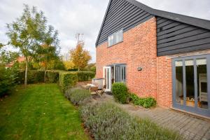 a brick house with a patio and a yard at Three Chantry Barns, Orford in Orford