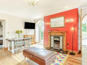 a living room with a red wall and a fireplace at Nightingale House in Ottery Saint Mary