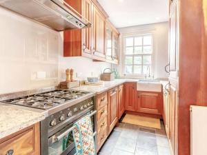 a kitchen with wooden cabinets and a stove top oven at Nightingale House in Ottery Saint Mary