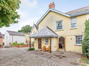 an exterior view of a yellow house with a driveway at Nightingale House in Ottery Saint Mary