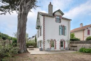 ein weißes Haus mit grünen Fenstern und einem Baum in der Unterkunft Maison de caractere a 100 metres de la plage in Le Pouliguen